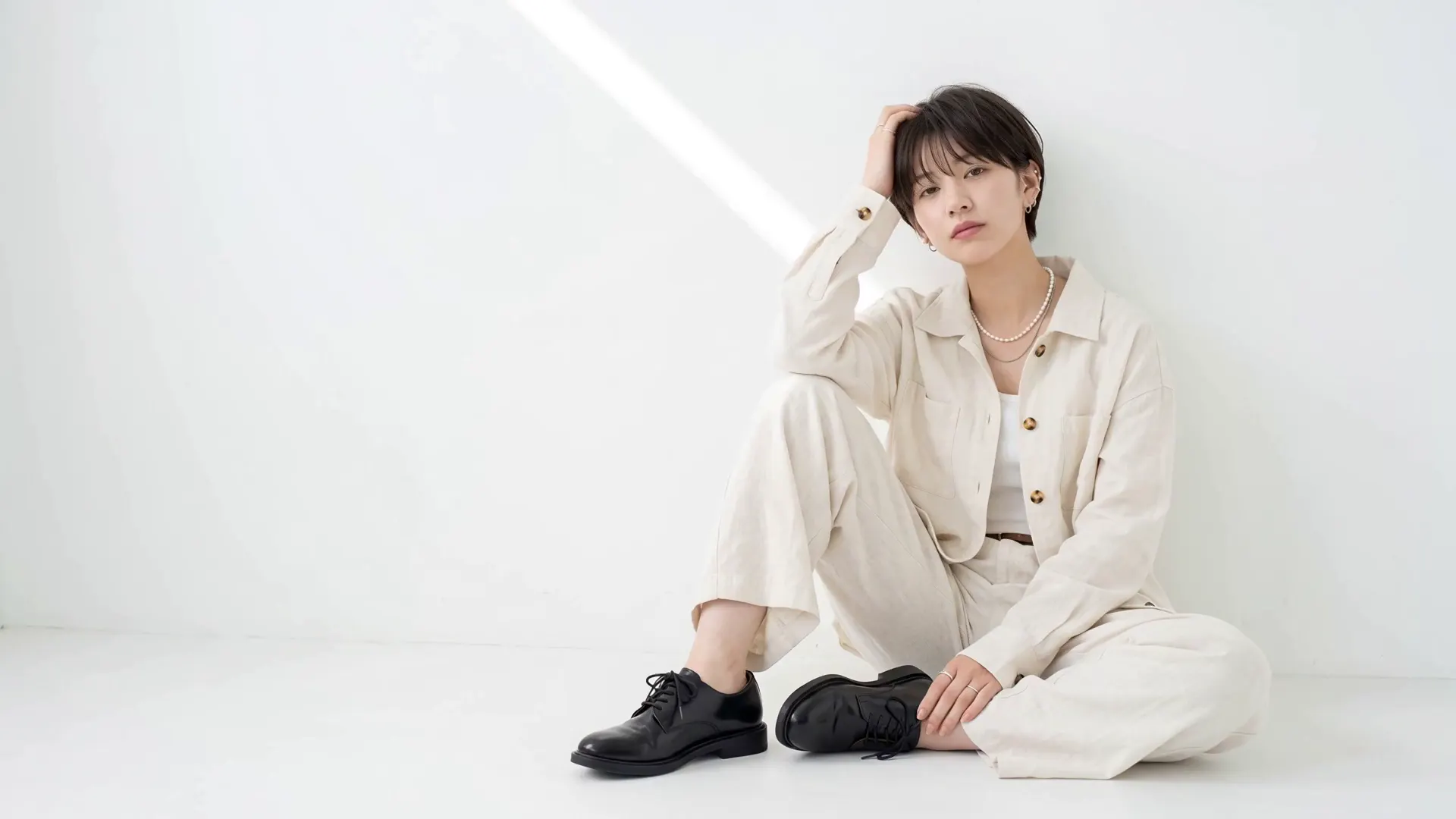 白いスタジオでポーズをとるショートヘアの女性と、カールヘアの男性